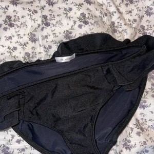 Bikini trosa - Ida Sjöstedt bikinitrosor med volang, aldrig använda och var rätt dyra. Köpta på Åhlens men minns ej priset🖤 Sitter täckade och rätt lowwaist men för mig med vanligtvis 36 så går de att dra upp så de får en snyggare passform! Passar 36 bra men kommer ej till användning!!