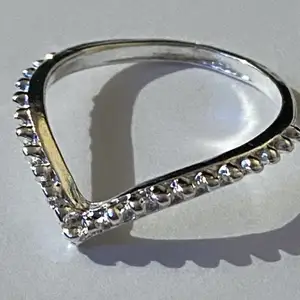 Silverring i form av ett “V” med små detaljer.