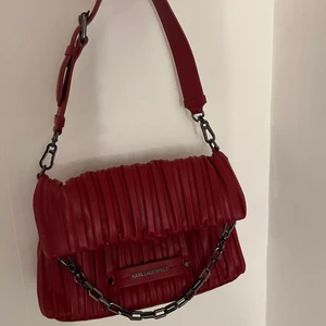 Karl Lagerfeld - kushion bag - Karl Lagerfeld - Kushion SM folded tote i färgen carmin/gun (röd). Kommer med prislapp på och med dustbag. Nypris 2395kr, köpt från Zalando men säljer då jag ej kan returen pga bruten förpackning. MÅTT: höjd: 32 cm, längd: 30 cm, Vidd: 10 cm, handtag: 14 cm