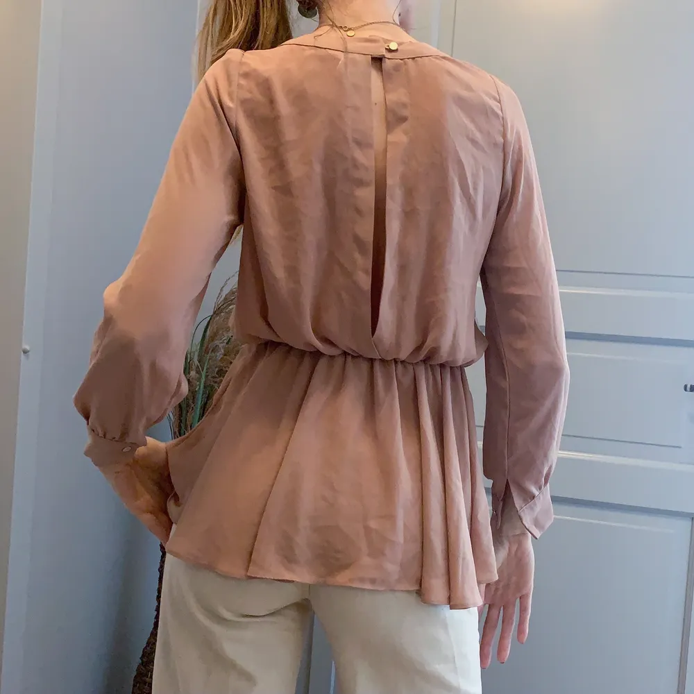 Beige blus med stretchigt band i midjan. Har en diskret öppning i ryggen. Storlek small. Från Style by Nuke. . Blusar.