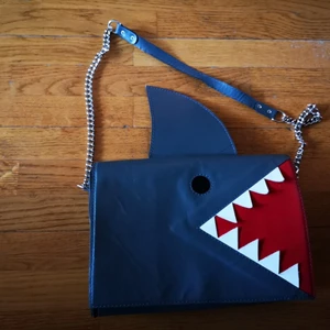 Hand made leather "Shark" bag - A stunning handmade bag by Bosnian designer Lucija Vrcic. The "Shark" bag is made of gray leather with red mouth detail in suade. Follow Lucia's unique bag design on Facebook and Instagram. 