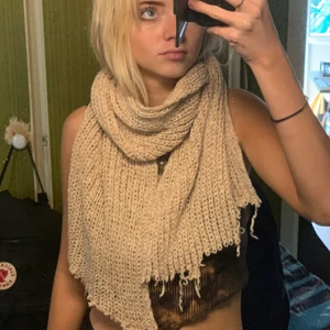 Halsduk - Beige stickad halsduk, är lite ”fransig” på ändarna.