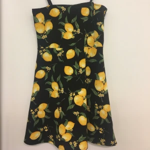 Klänning  - Svart klänning med citronmönster på. Använd en midsommarafton. Sitter fint på. 