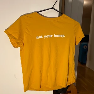 Senapsgul tshirt ”Not your honey” - Sjukt snygg senapsgul tshirt från Gina tricot i storlek XS. Det står ”Not your honey” på den. Den har några små hål, men de märks inte när man har på den:) Pris kan diskuteras. Frakt betalas av köpare.