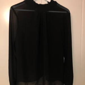 Blus  - Nästan aldrig använd blus. Lite genomskinlig i materialet med knappt man knäpper bak vid nacken. Jättefin!