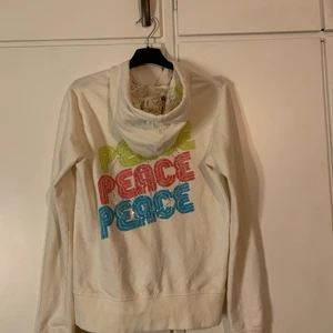 munkjacka  - en vit zip up hoodie med rhinsonse på i st S med tex peace skriver på ryggen 