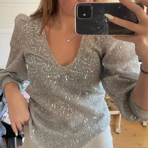 Glittrig topp - Fin topp som aldrig är använd. U-ringad och trekvartslånga ärmar.