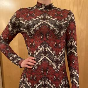 A red beautifully patterned 70s retro dress with flowers and symmetrical lines by Springfield. 