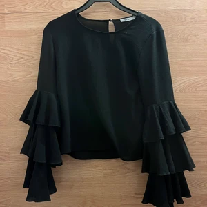 Blus med volanger - En supergullig svart blus från NA-KD i tunt material med volanger på ärmarna! Hör av er vid frågor eller fler bilder💞