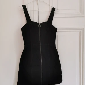 Klänning m hängslen, jeansklänning - Svart klänning med hängslen i mjukt stretchigt jeanstyg. Storlekslappen är tyvärr bortklippt, men passar 34/36. Dragkedja längs hela framsidan, går att öppna helt. Köparen står för frakten, kan även hämtas i Malmö! 