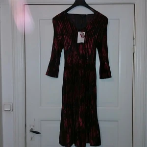 KRISS sweden - Långärmad klännng som passar den lite som är lite kraftga. Tyget är tybart och både ni med M och L lär passa deta plagg perfekt. Ny och aldrig använd.