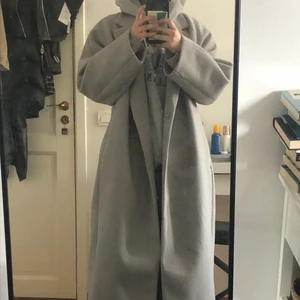 Lång oversized grå kappa  - Jättesnygg vårkappa som är i nytt skick förutom en liten slitning längst, kappan går cirkus 1dm över mina fötter på mig som är 160 lång!