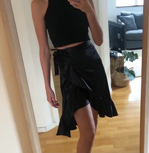 Svart kjol - Jättefin svart kjol i storlek S men man knyter hur tajt eller löst man vill ha den, använd ett fåtal gånger, materialet är lite skimrig satin