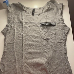 Grå tröja - Den har en liten detalj vid lilla fickan, helt oanvänd.