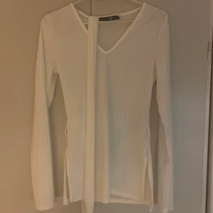 Vit boohoo tröja storlek 36 , modell tall - Vit boohoo tröja. ❌ genomseende ❌  , Slits vid båda sidorna och ett band runt midjan . Ganska så v-ringad . Aldrig använt bara testat. Längden är bra på mig som är 159 men tyvärr ser man lite igenom
