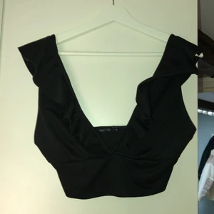 Urringad svart topp från NLYONE - Kortare svart topp, urringad bak och fram, snygg till fest! Köpt på Nelly storlek M passar även S