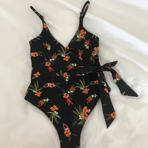 Baddräkt  - Jättefin baddräkt i blommönster med rosett och djup rygg, aldrig använd☀️