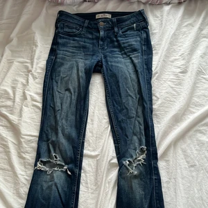 Lågmidjade jeans - Lågmidjade bootcutjeans med hål på knäna från Hollister i storlek w23 l33. Kan mötas upp på Lidingö eller i centrala Stockholm.