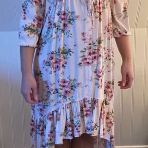 Ljuvlig sommarklänning  - Blommig sval sommarklänning med knyte i midijan. Den är long bak till och lite kortare fram. Aldrig använd och ny pris 799kr