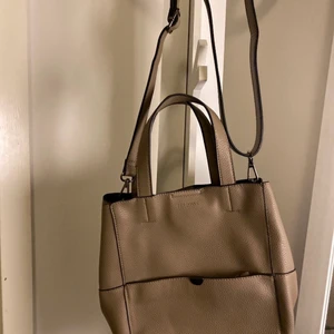 Helt ny väska från Don Donna!!  - Söt väska/ handväska från Don Donna, aldrig använd! Så den är som helt ny!!  (Grå/beige/brunt )läder  Bra med fack på både utsidan och insidan! Diskreta loggor med Don Donna på framsidan och i mittenfacket!  Justerbart axelband som även är avtagbart samt handtag i mitten vilket ger möjlighet till en allsidig snygg liten väska!