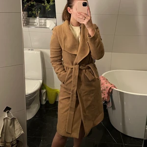 Beige kappa - Varm beige kappa, näst intill oanvänd. I nycksick. Med fickor och skärp i midjan. 