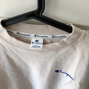 Champion Sweatshirt stl M  - Beige/offwhite färgad sweatshirt från Champion storlek M. Dragsnöre ifall man vill göra den tajt nertill, superskön och i oversized modell men också lite kortare. Bra skick, inte använts mycket, nypris: 999kr