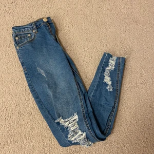 Jeans storlek 34 - Jeans från BooHoo med slitna knän 