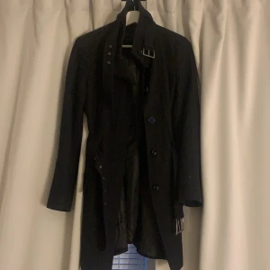 Svart tjock kappa - En svart tjock kappa med midje band och knappar