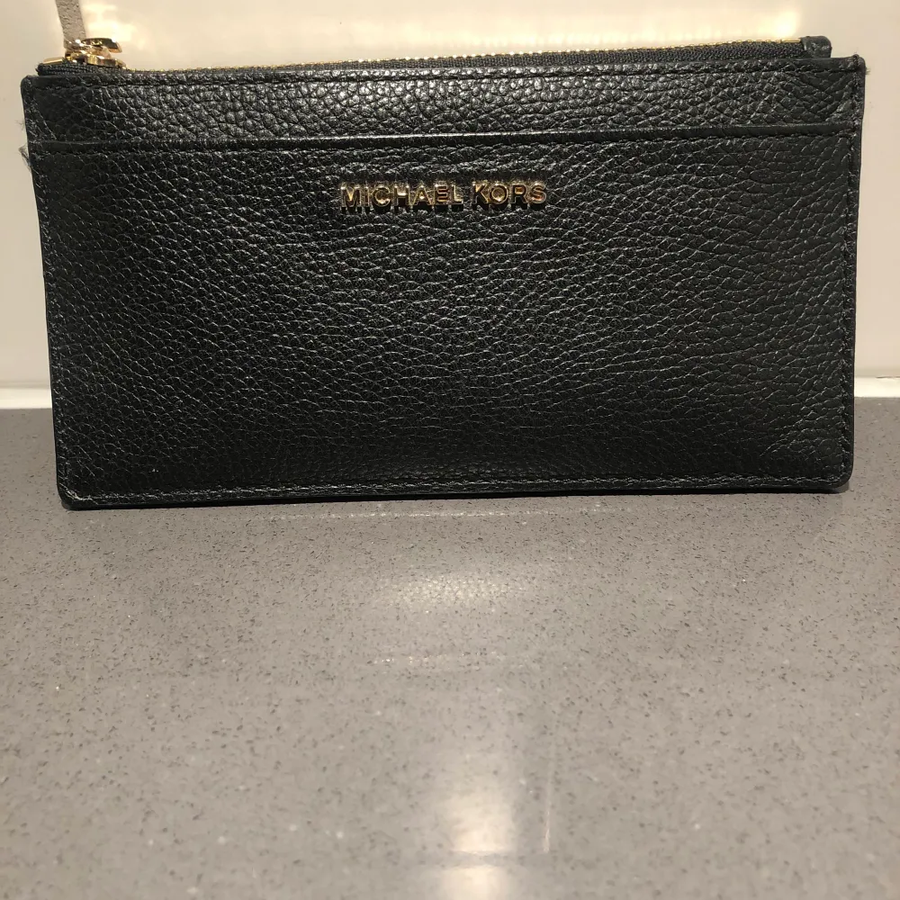 En äkta michael kors plånbok i svart läder! Lätt använd!  inga skador dock tappat minimal färg vid dragkedjan. Accessoarer.