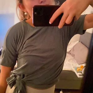 Grön t-shirt med knytning på - Jättefin grön t-Shirt som har knytning på sidan om (färgen syns bättre på andra bilden) endast använd vid ett fåtal tillfällen därför i super fint skick. (Skrynklig för att den har legat i en låda) 