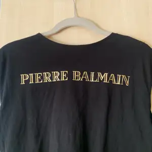 Svart T-shirt från Balmain med guldknappar vid axlarna, använd några få gånger bara så tröjan är i bra skick! 