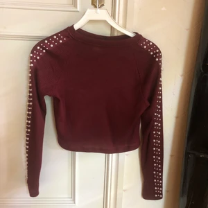Vinröd ribbad tröja med pärlor på ärmarna  - Fin vinröd ribbad långärmad tröja med pärlor längs ärmarna. Köpt på H&M avdelning divided.    Använd några fåtal gånger  Storlek S    100% polyester 