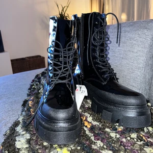 Svarta boots - Svart grova lackade boots med snörning! Suuuuuupersnygga, men köpte fel storlek! Använda en gång, så jättebra skick. Nypris 449kr. Storleken är 39 men passar absolut 38 också