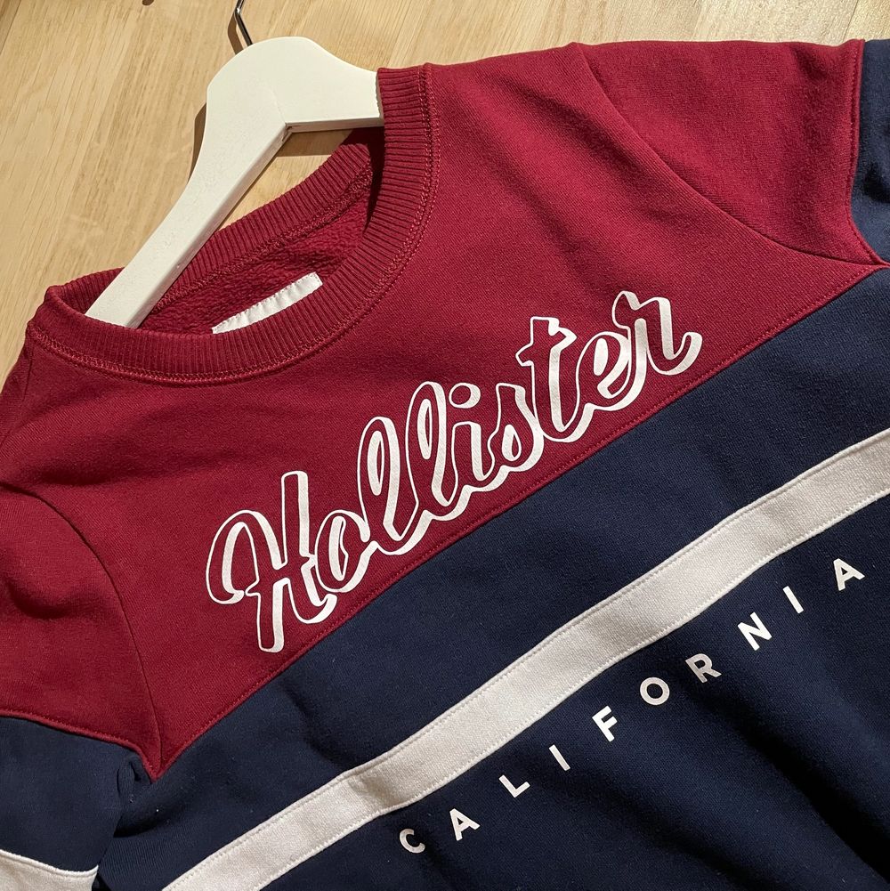 Red, dark blue and white sweatshirt with the logo “Hollister California”. Very good condition. I can send the product but the buyer is paying for it. —— Röd, mörkblå och vit sweatshirt med logotypen