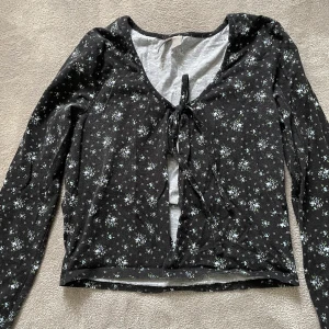 Söt blommig tröja med knytning framtill - Långärmad tröja i ett mjukt bomullstyg med blå blommor, storlek 36 men skulle även passa en 38 eftersom den är stretchig! 