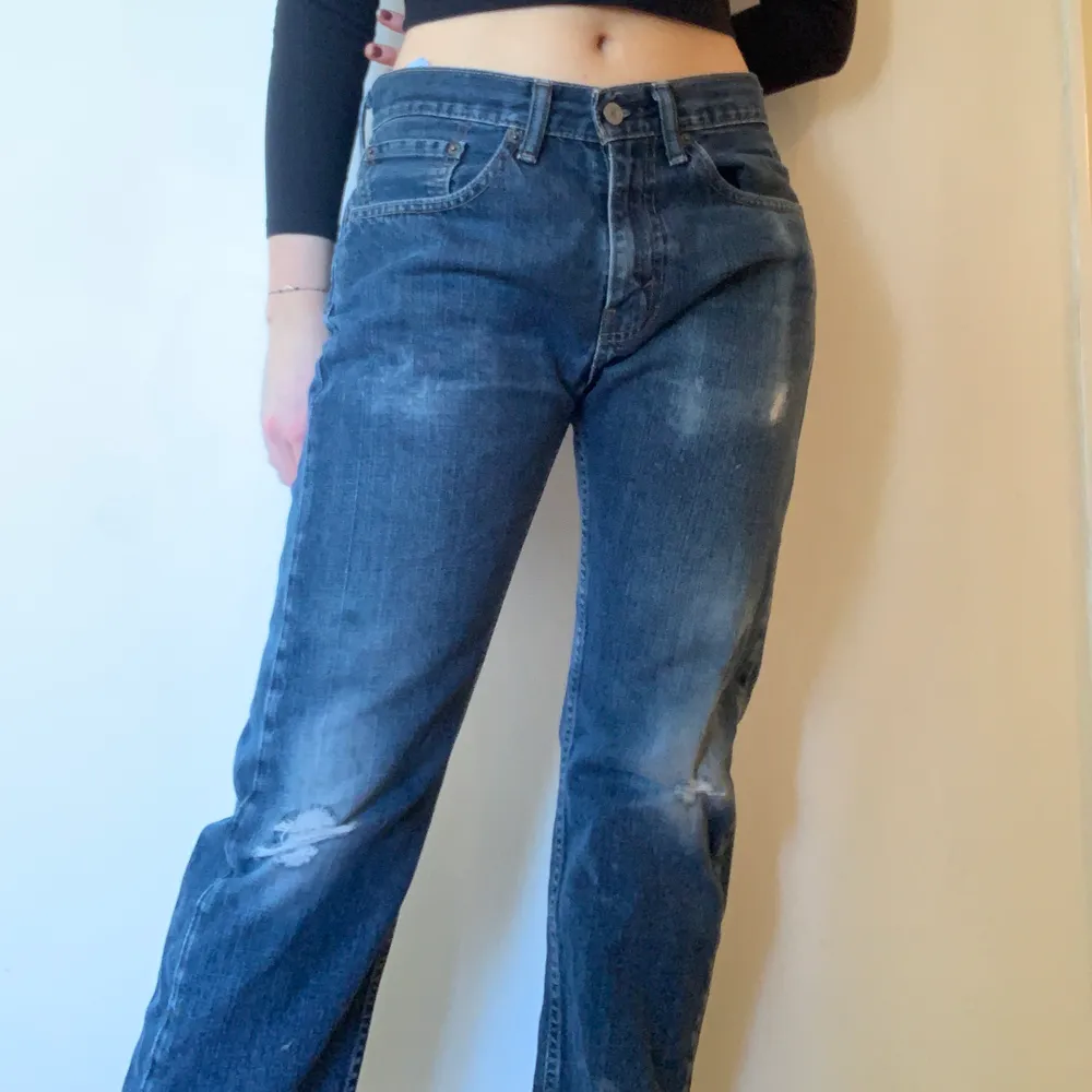 Blåa jeans köpta från Beyond Retro! Supersnygga med hål i och schysst längd! Har en färgfläck på högra benet.. Jeans & Byxor.