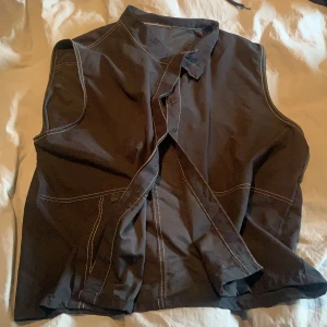 Svart väst med vita sömmar - Västen är tunn så den passar perfekt till sommaren. Frakten ingår i priset.