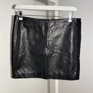 Skinnkjol med mockadetaljer  - Äkta skinnskjol. Mjuk i skinnet. Mocka på sidorna och dragkedja bak 