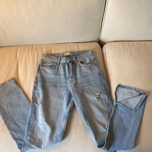 Gina tricot slitsade jeans  - Ljusa jeans med slitningar. Medelhög midja. En slits vid foten. Funkar till alla outfits! 