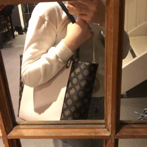 En fin Guess väska  - Jag säljer denna fina Guess väska. Den har blivit andvänd några få gånger. Men är i ett mycket bra skick. Inuti väskan har den 3 lite mindre fack där man tex kan lägga solglasögon, laddare osv och ett stort. (Frakten är inräknad i priset)