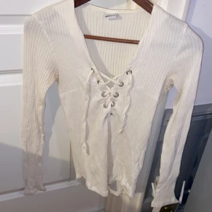 Vit tröja med snörning  - Vit ribbad tröja med snörning framtill från Gina tricot i storlek S. Sjukt snygg på och bekväm! Fler bilder och mer info går att få🥰