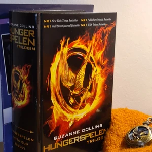 Hunger Games-kit - Hunger Games för hela slanten! 🔥 Alla delar i trilogin inbunden i en och samma bok; ett jättefint fick-ur med härmskrikesymbolen på (batteri medföljer ej). 🧡 BONUS: ett häfte om Josh Hutcherson som spelar i filmerna. 🌟   OBS: FICKURET ÄR SÅLT