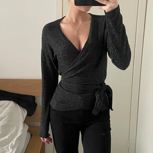 Vero Moda topp - Jättemysig topp från vero Moda i en mörkgrå färg. Omlott och knyts runt midjan, lång i armarna. Knappt använd så den är i fint skick