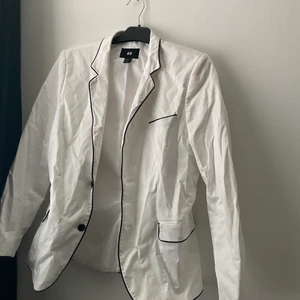 Vit kavaj med svarta detaljer - En vit kavaj, skrynklig men det går att lösa. Ganska oanvänd. 