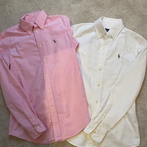 Klassiska Ralph lauren skjortor - Stilren och tidslös vit och rosa vardagsskjorta från Ralph Lauren i custom fit strl XS/0, inköpta i USA på Ralph Lauren store. 150kr/skjorta alt. 250kr för båda skjortor. Väldigt sparsamt använda! Nypris 995kr/skjorta. (OBS! Den vita är såld.)