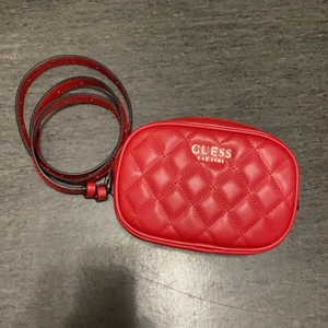 Guess väska röd  - Köpte den i new york men använde den en gång för två år sen och den hamnade i bakre delen av garderoben. Jätte söt och smart väska för utekvällar när man bara behöver nycklar, telefon och plånbok.