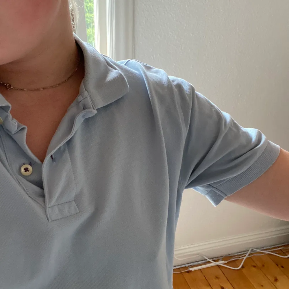 Blå piké i en mycket fin blå färg. Köpt secondhand så skulle uppskatta att den är en 40 i en damstorlek. Jag är en 38/S och sen sitter lite oversized på mig . T-shirts.