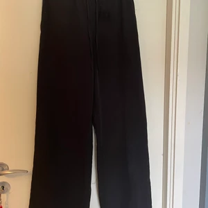 Kostymbyxor  - Vida/breda kostymbyxor med vita detaljer/ränder längd med sidorna (se bild). Resår i midjan