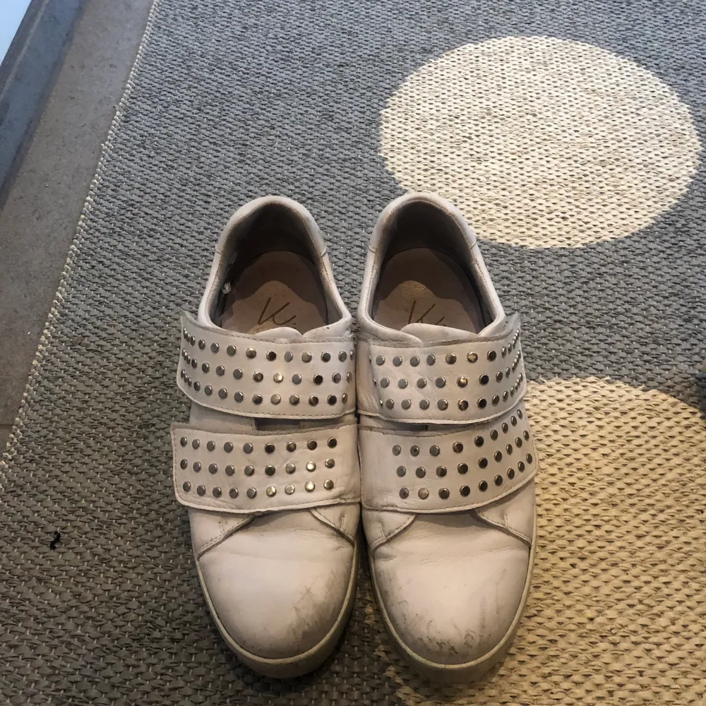 Ett par vita coola skor med nittar och två resårband, använt mycket och har lite skrapsår få framsidan. Platån är lite högre än vanliga sneakers.. Skor.