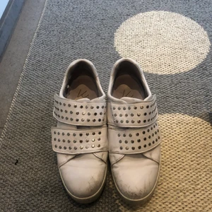 Ett par snygga sneakers med nittar!! - Ett par vita coola skor med nittar och två resårband, använt mycket och har lite skrapsår få framsidan. Platån är lite högre än vanliga sneakers.